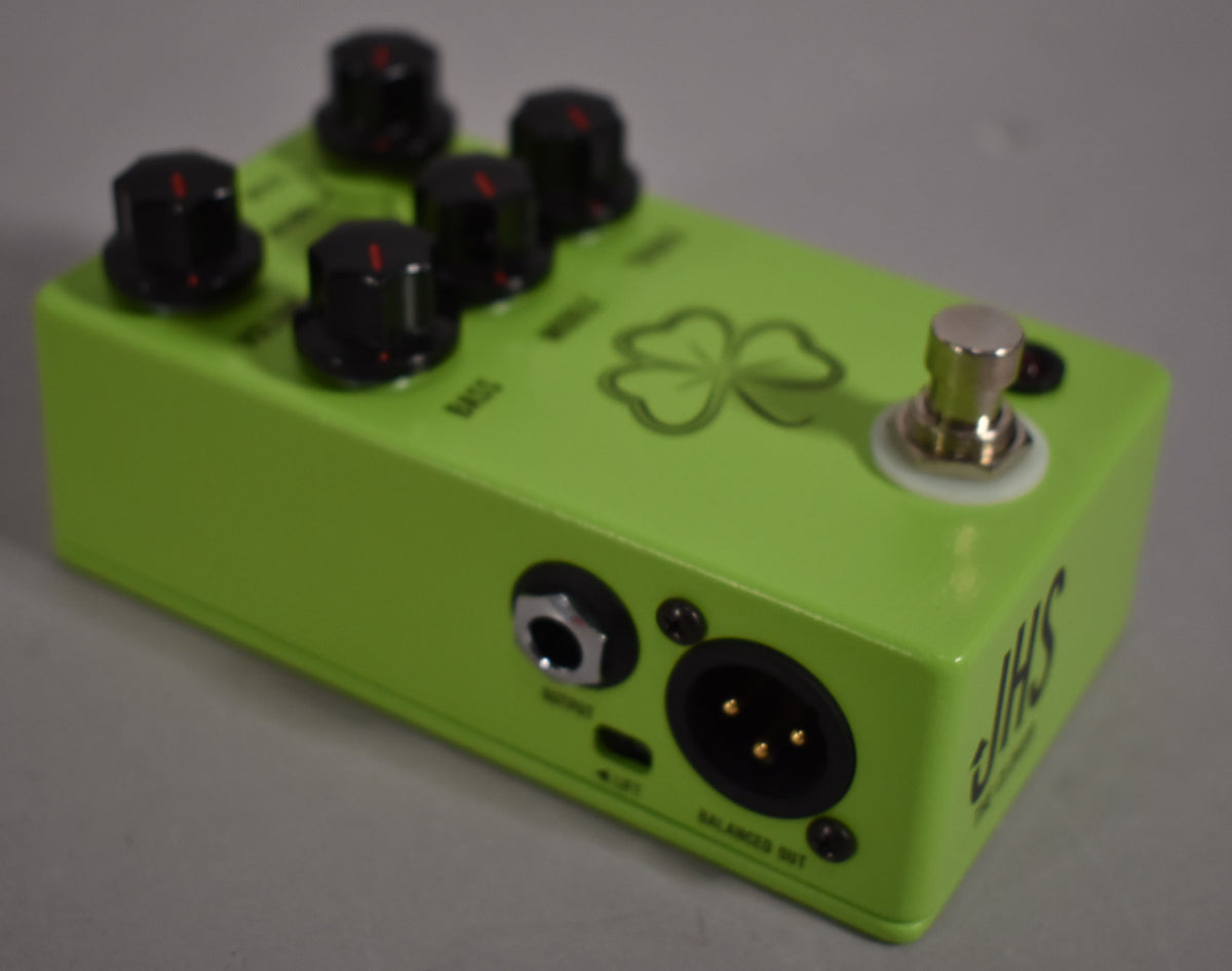 A bright green pedal, viewed from above and the front-left, with five black control knobs, a footswitch, and two output jacks.