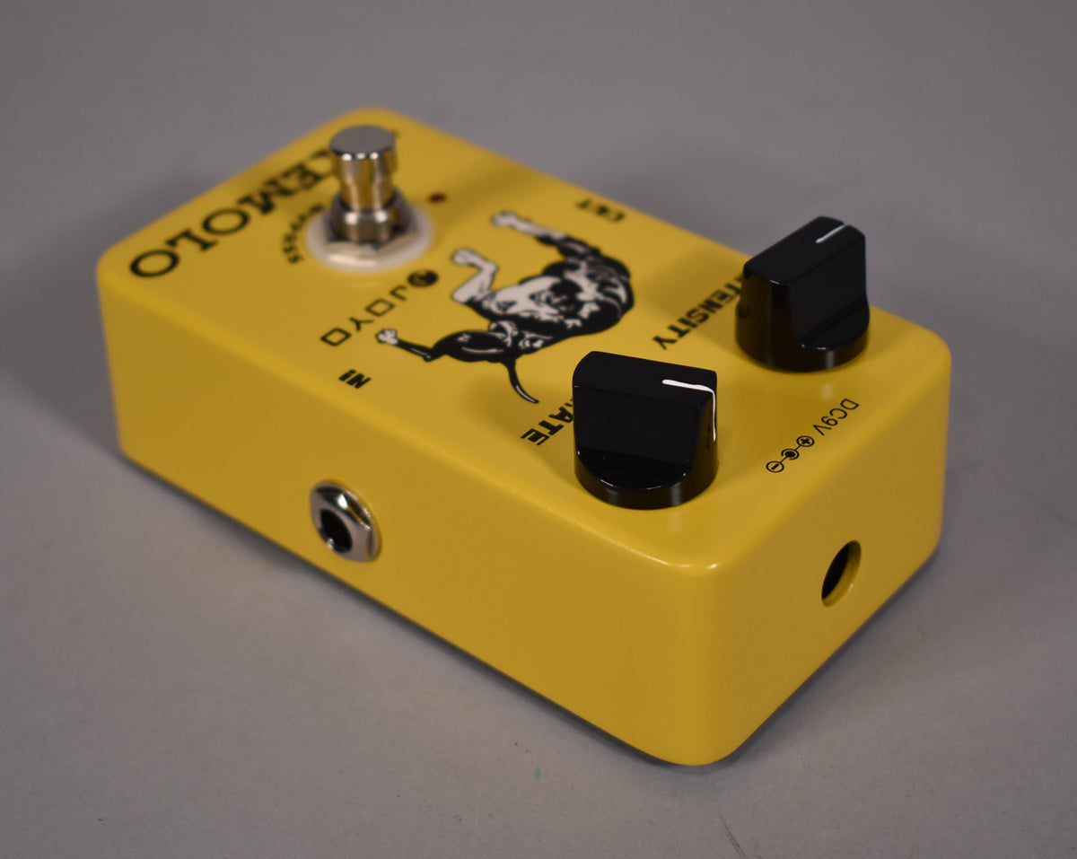 Bright yellow pedal with a dalmatian graphic, two black control knobs, a chrome footswitch, and input jacks on the left and right.