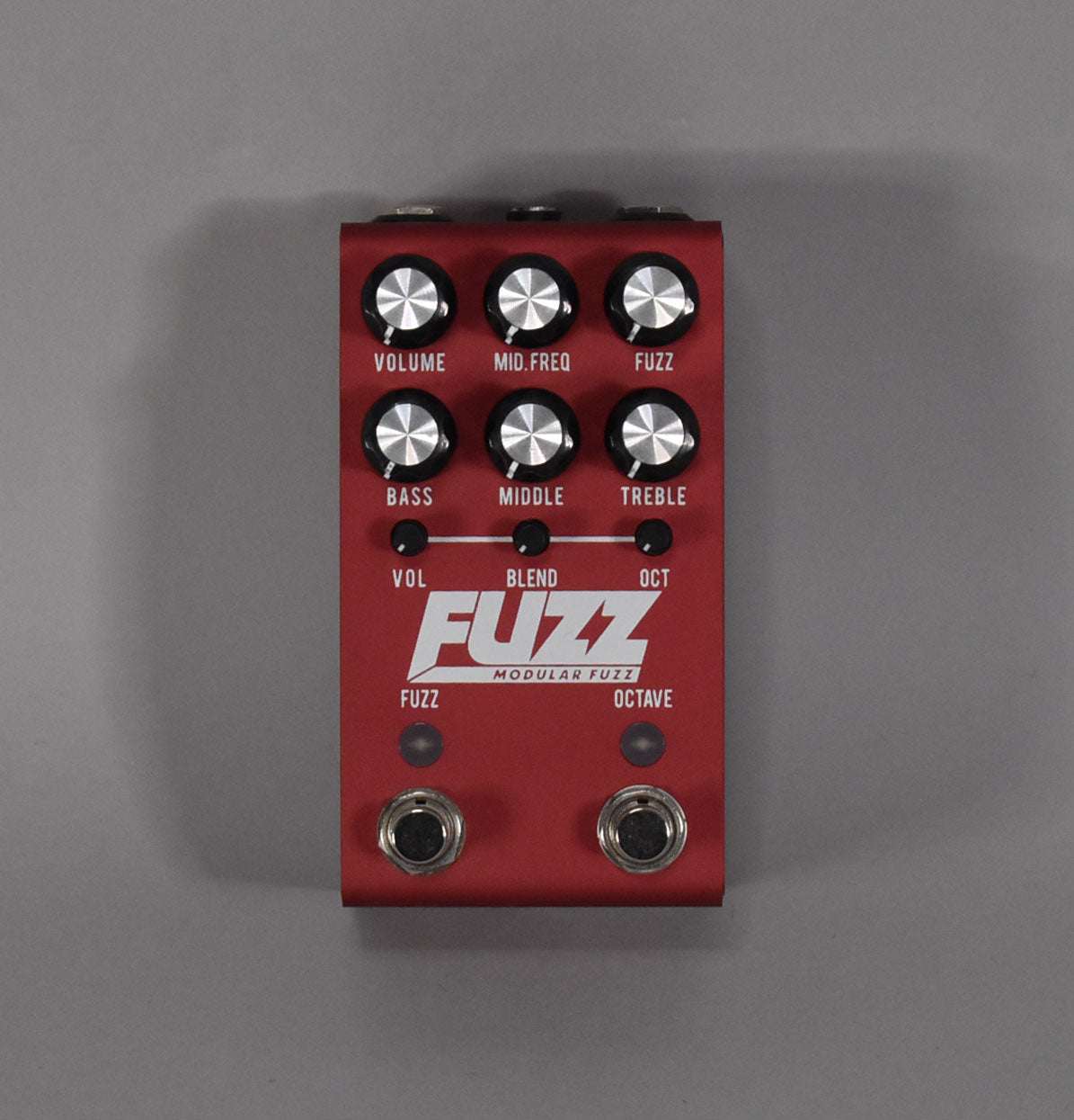 Top-down view of a dark red pedal with six black-and-silver knobs, three small black knobs, and two footswitches.
