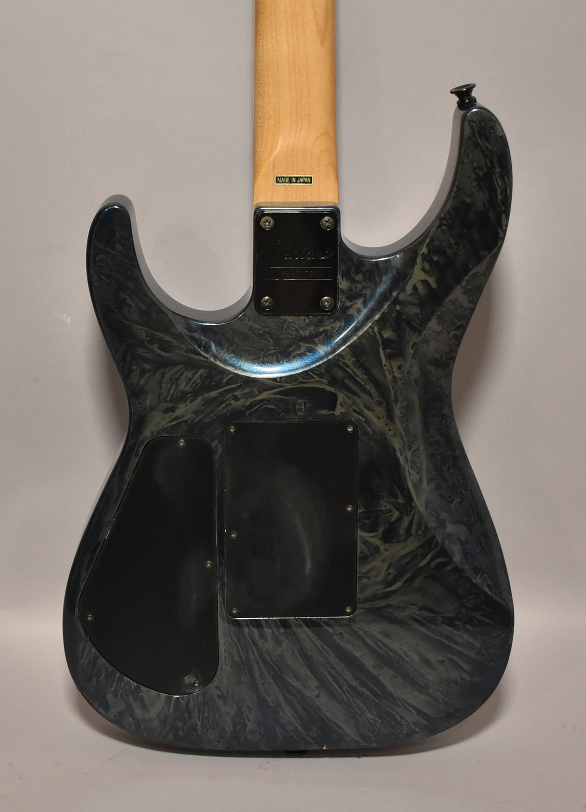 The back of a blue swirl guitar, showing the neck joint, two black control cavity covers, and a black strap button.