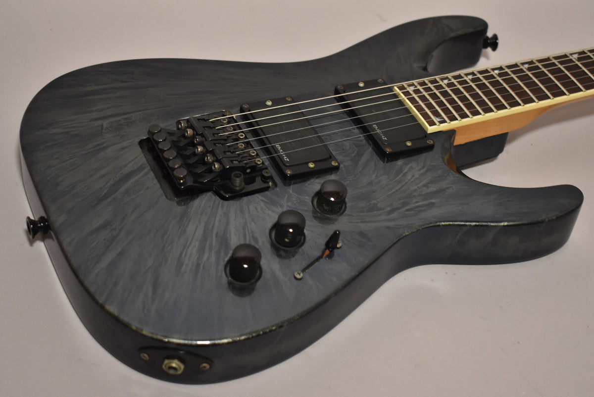 The blue swirl electric guitar body, angled from the lower bout, shows two humbuckers, a Floyd Rose bridge, and three control knobs.