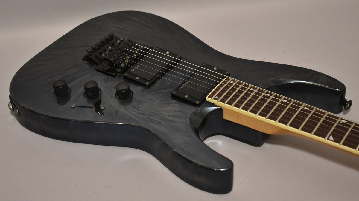 Blue swirl electric guitar body, angled from the lower bout, showing black humbuckers, Floyd Rose bridge, and three control knobs.