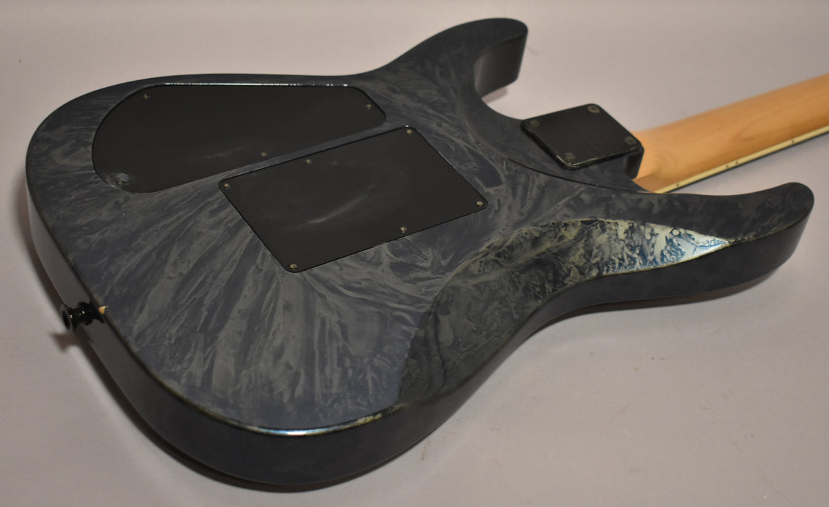 The guitar's back shows a blue swirl finish, black control cavity covers, and a worn patch on the lower horn.