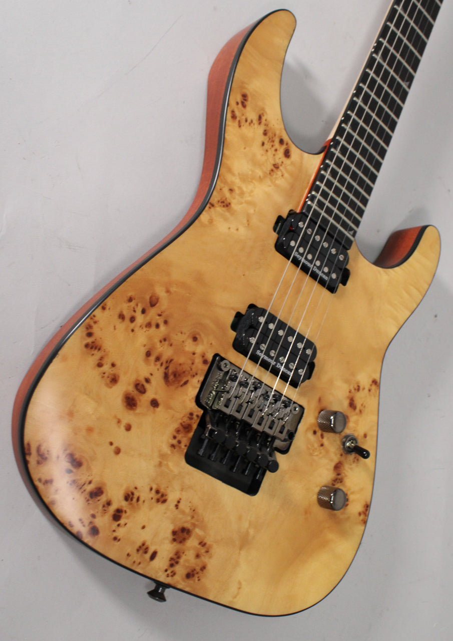 Angled view of a light wood guitar with dark burl figuring, black hardware, two humbuckers, a Floyd Rose bridge, and two chrome knobs.