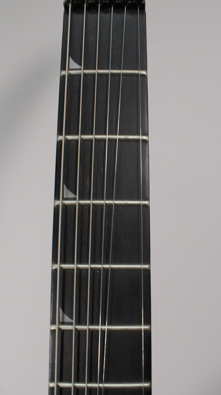 Close-up of the dark fretboard with six strings, showing two pearloid sharkfin inlays on the 3rd and 5th frets.