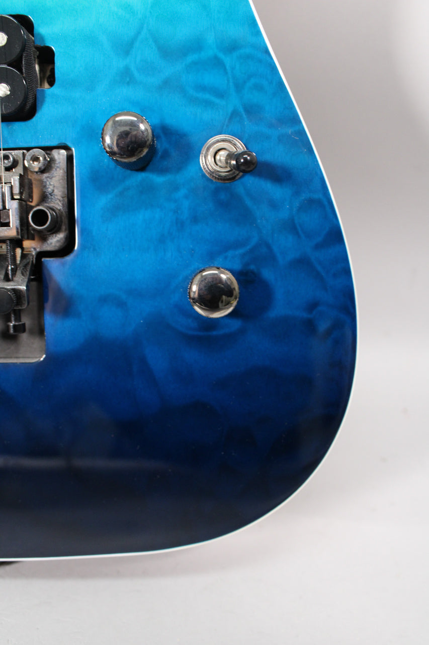 Close-up of the guitar's lower body, showing the Caribbean Blue Fade finish, two chrome control knobs, and a black pickup selector switch.