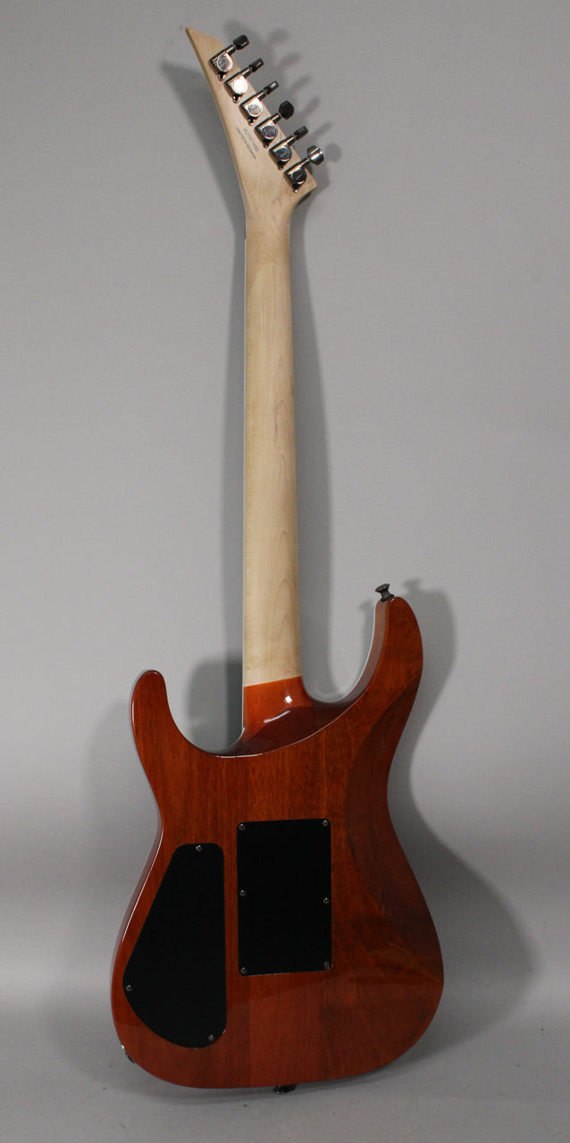 The guitar's back is shown, revealing a natural wood neck and a reddish-brown body with two black control cavity covers.