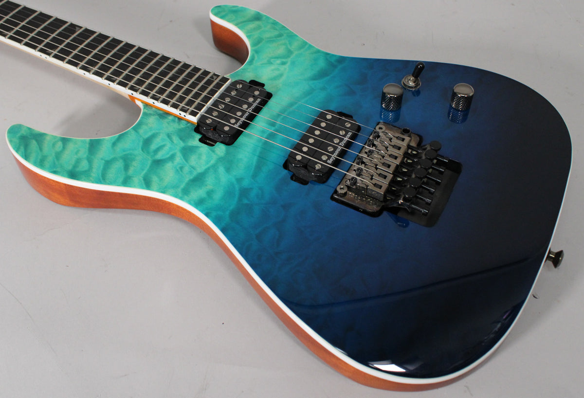 Close-up of the guitar body, showing the quilted maple finish fading from teal to dark blue, with two humbuckers and a Floyd Rose bridge.