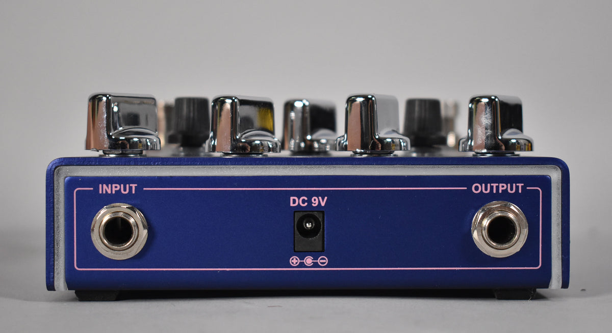 The purple pedal's rear panel is shown, featuring input, output, and DC 9V jacks, with several chrome knobs visible above.