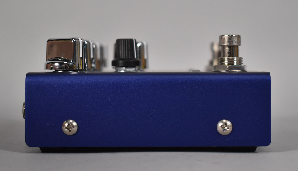 Side view of the purple pedal, showing its textured finish, two silver screws, and the bottom edges of several chrome and black controls.