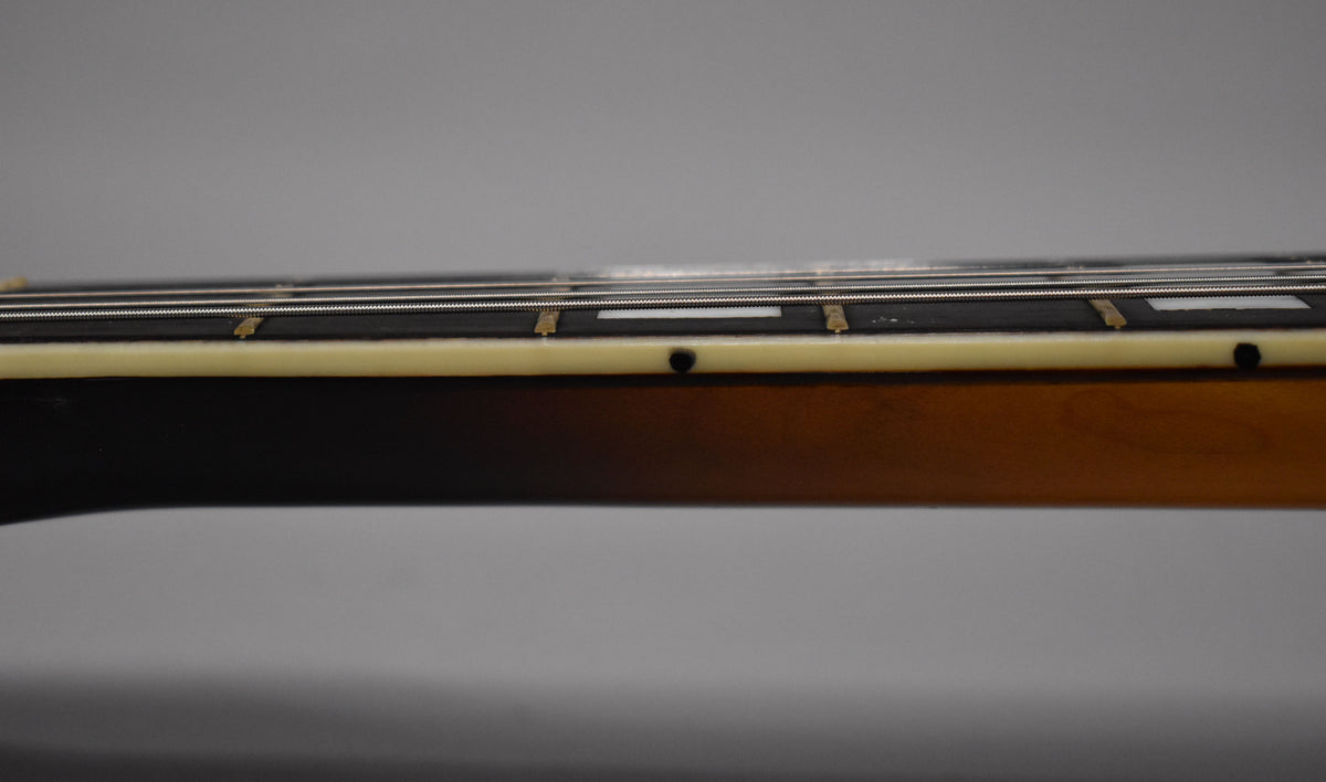 Close-up of the sunburst neck's side, showing cream binding with black dot markers and rectangular fretboard inlays.