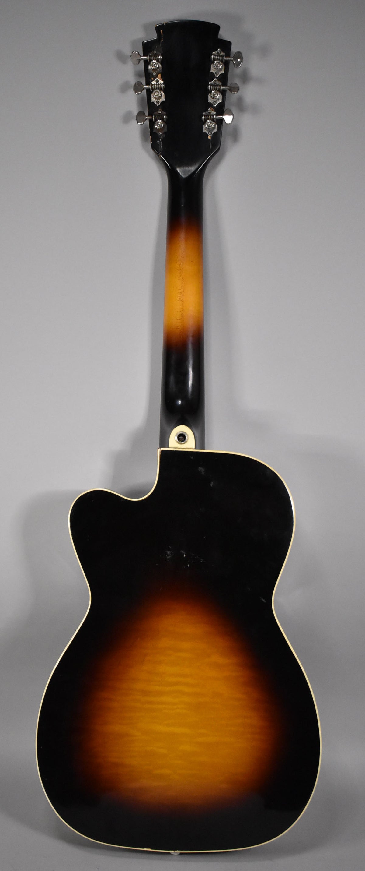 The back of a sunburst archtop guitar with a cutaway, showing a dark headstock, six chrome tuners, and some finish wear.