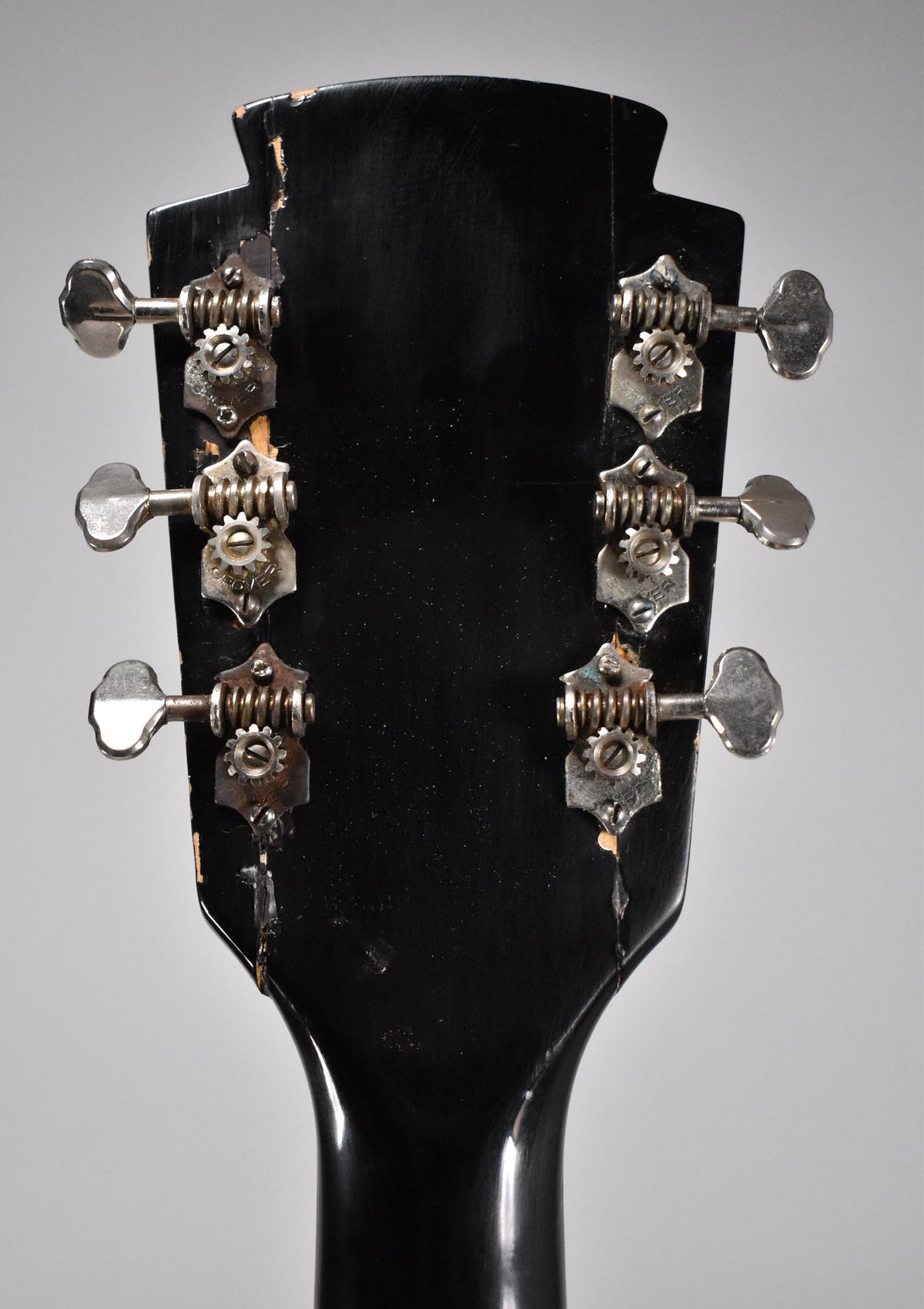 Rear view of the black headstock and top of the neck, showing six open-gear tuners with metal buttons and significant finish wear.
