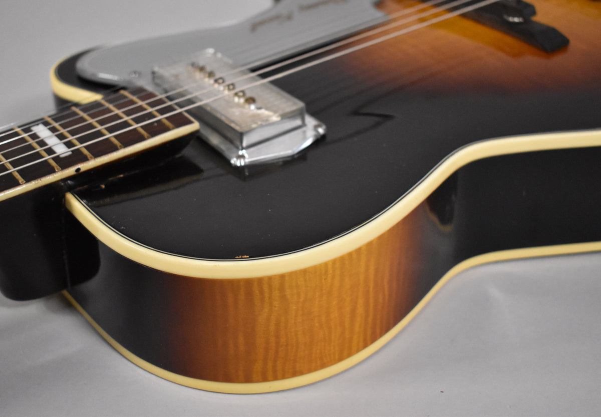 Close-up of the guitar's lower bout, showing the sunburst finish, cream binding, and a chrome pickup with a silver pickguard.
