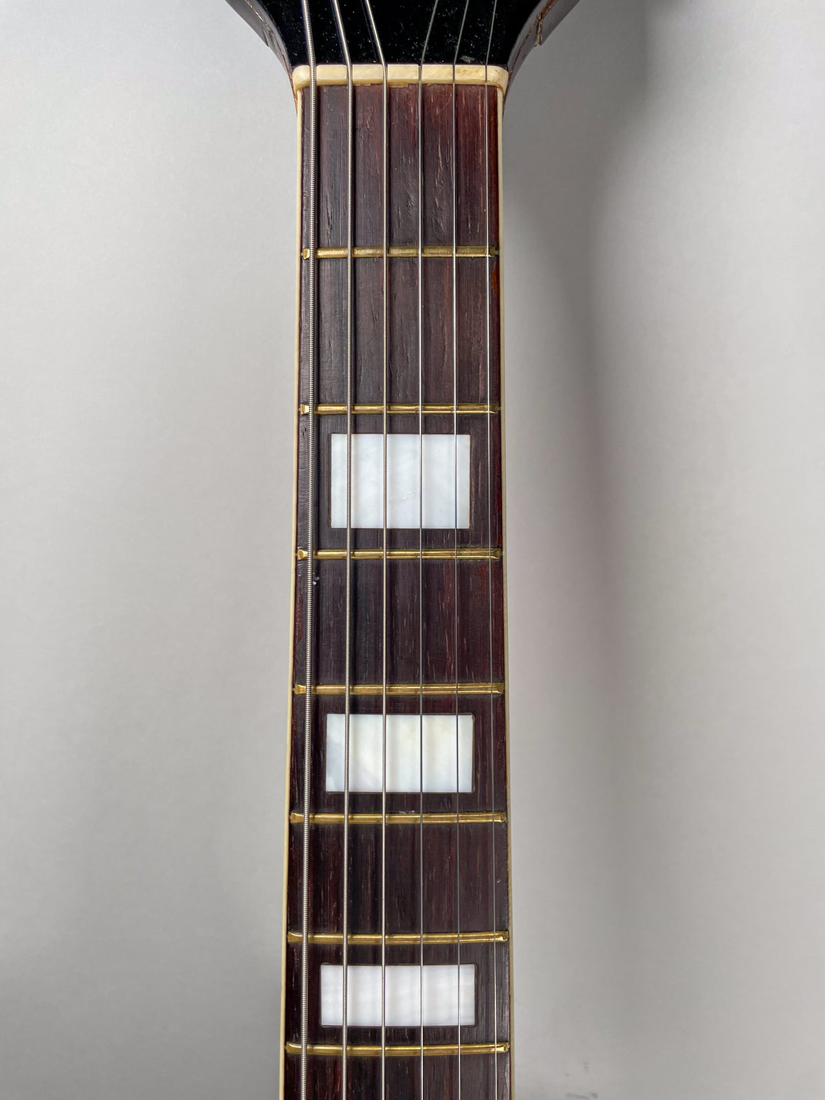 Close-up of the dark brown fretboard with rectangular mother-of-pearl inlays, showing light wear on the frets and wood.