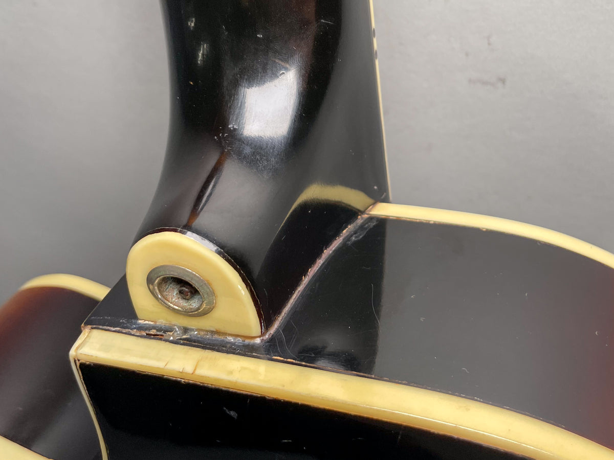 Close-up of the guitar's neck heel and cutaway, showing the dark sunburst finish, cream binding, and some finish wear and checking.
