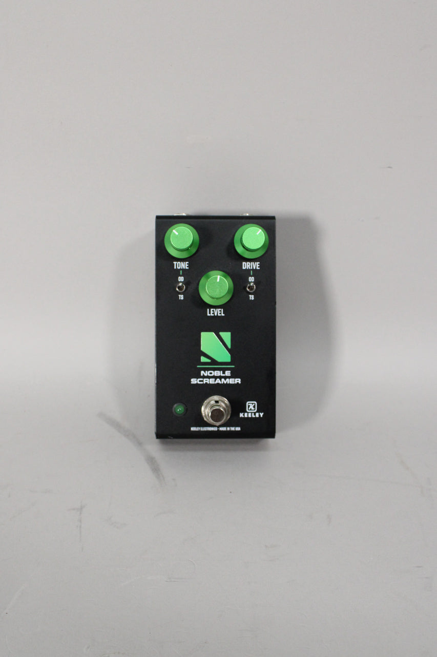 Black pedal with three bright green knobs for Tone, Drive, and Level, plus two mini-toggle switches and a footswitch.