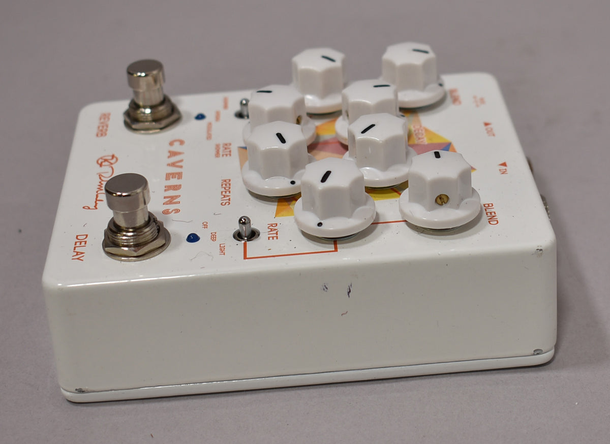 A white guitar pedal, viewed from the front-right, showing two footswitches, a toggle switch, and eight white control knobs.
