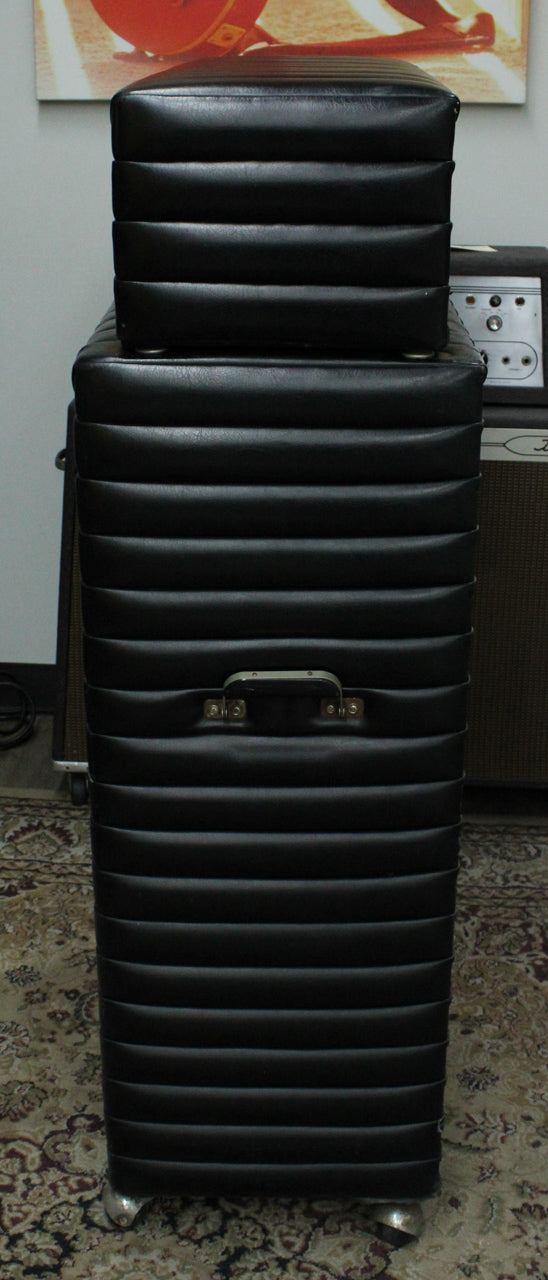 Full-height front view of the black tuck-and-roll amp head and cab, showing the handle and two bottom casters.