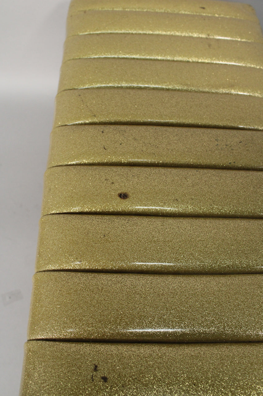 Close-up of the gold sparkle finish, showing horizontal padded segments with some dark scuffs and a small brown mark.