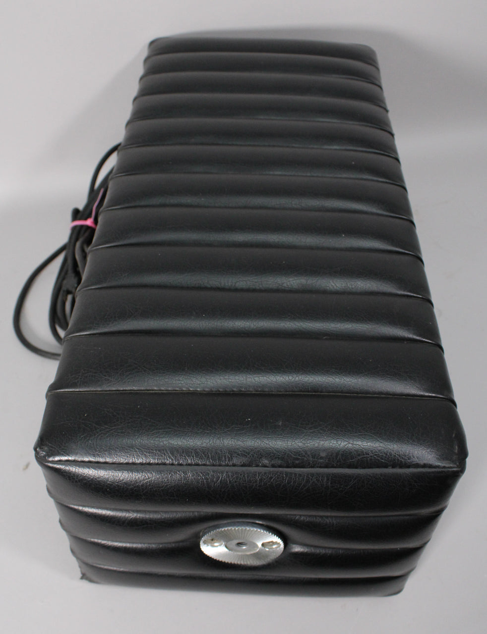 The black tuck-and-roll amp head is viewed from above, showing its ribbed top and a single silver knob on the front.