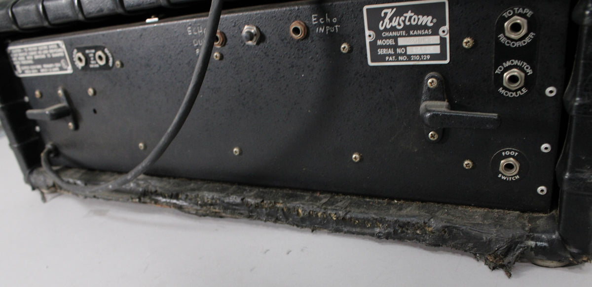 The black textured rear panel of the amp head shows various inputs, a data plate, and heavy wear along the bottom edge.