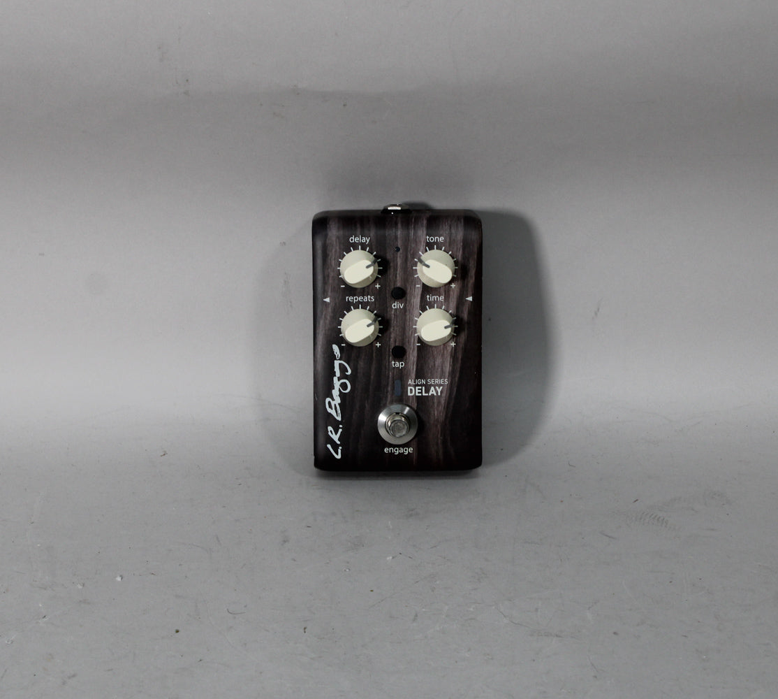 A dark woodgrain-finish delay pedal with six cream-colored control knobs and a chrome footswitch, viewed from the front.