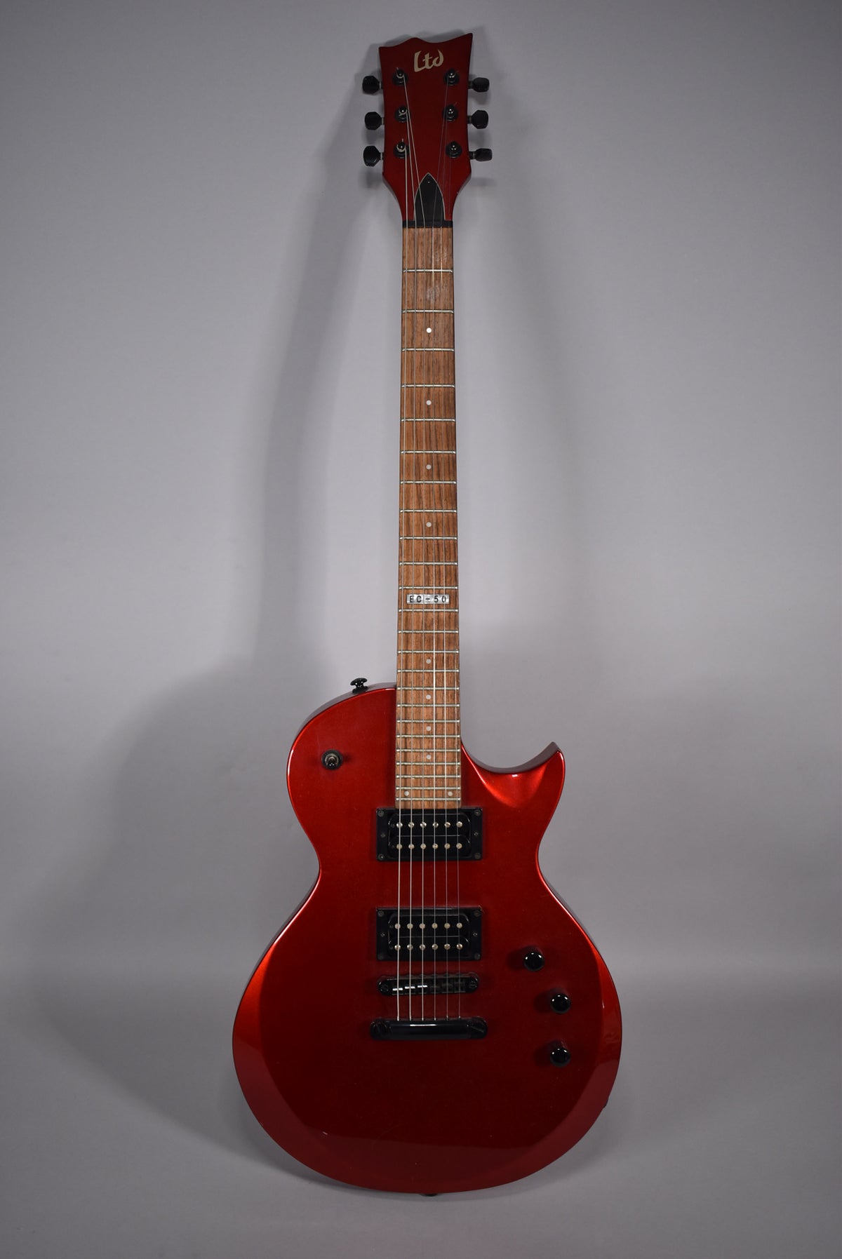 Full front view of a metallic red electric guitar with black hardware, two humbucker pickups, and three control knobs.