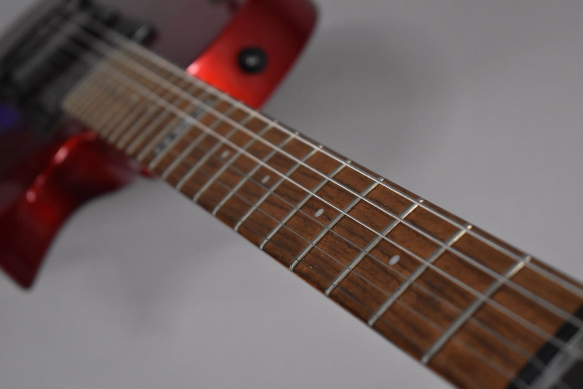 Close-up of the guitar's dark brown fretboard with white dot inlays, angled from the body, showing the red finish of the upper bout.