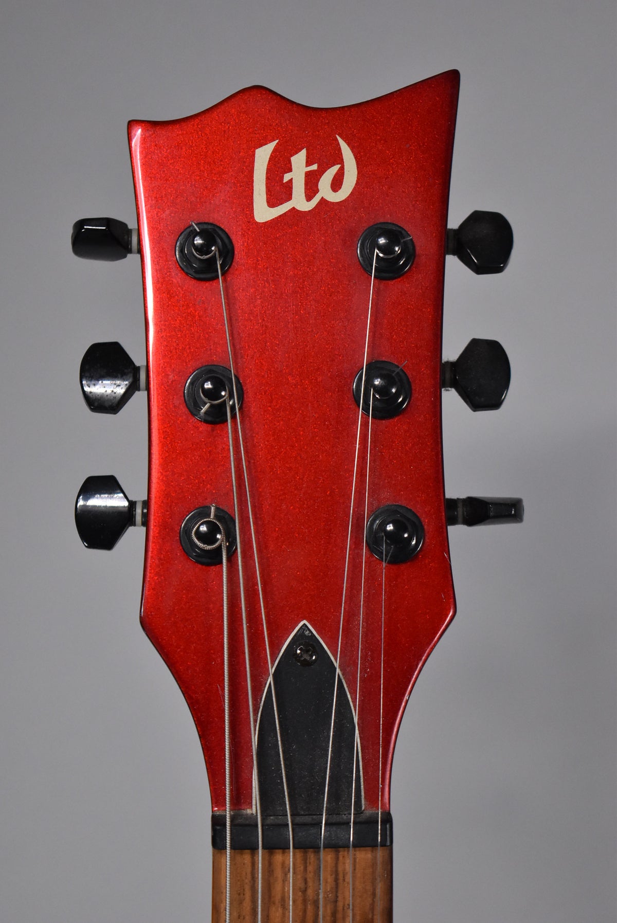 Close-up of the guitar's red sparkle headstock with six black tuners, showing some minor scuffs and wear.
