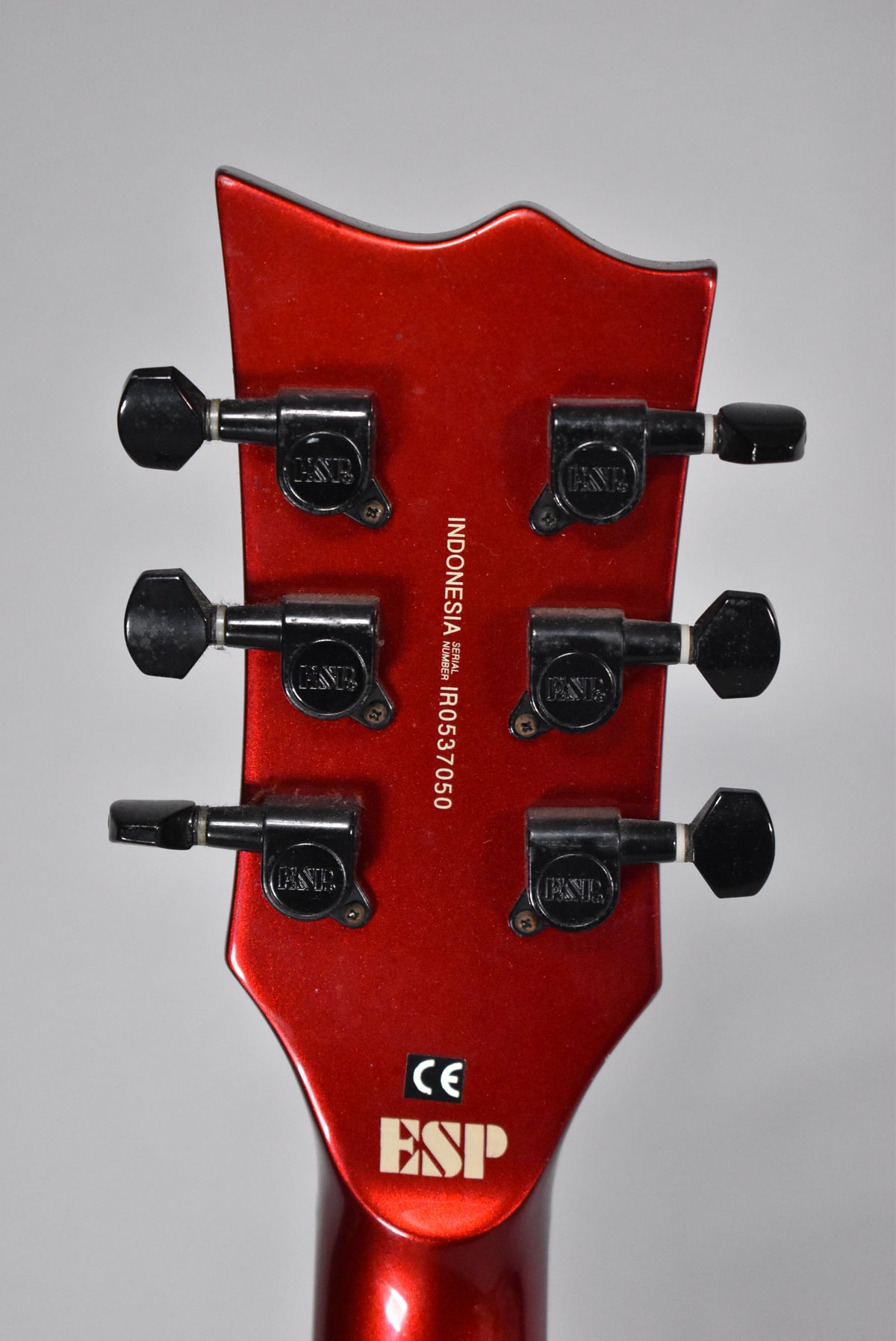 Rear view of the red metallic headstock, showing six black tuning machines and the serial number "IR0537050".