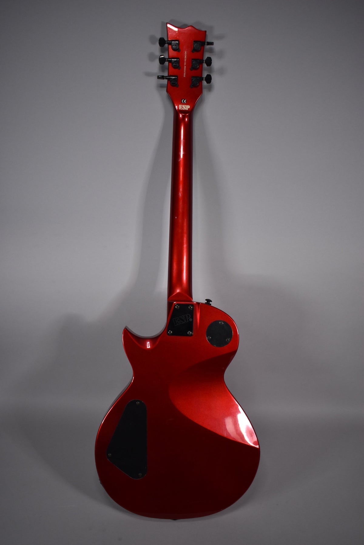 Full rear view of a metallic red electric guitar with black hardware, showing the headstock, neck, and body with control cavity covers.