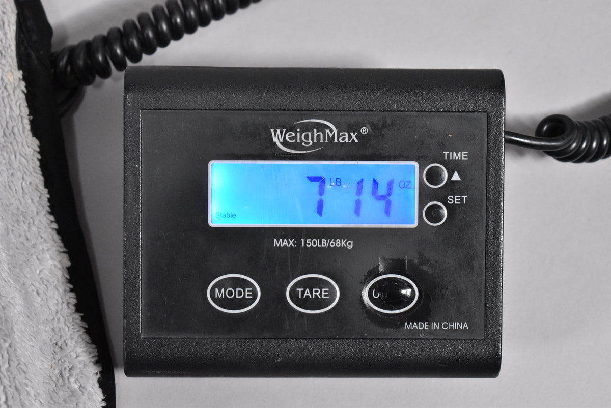A close-up of a digital scale displaying "7 LB. 14 OZ." in blue, with a coiled black cable visible on the right.