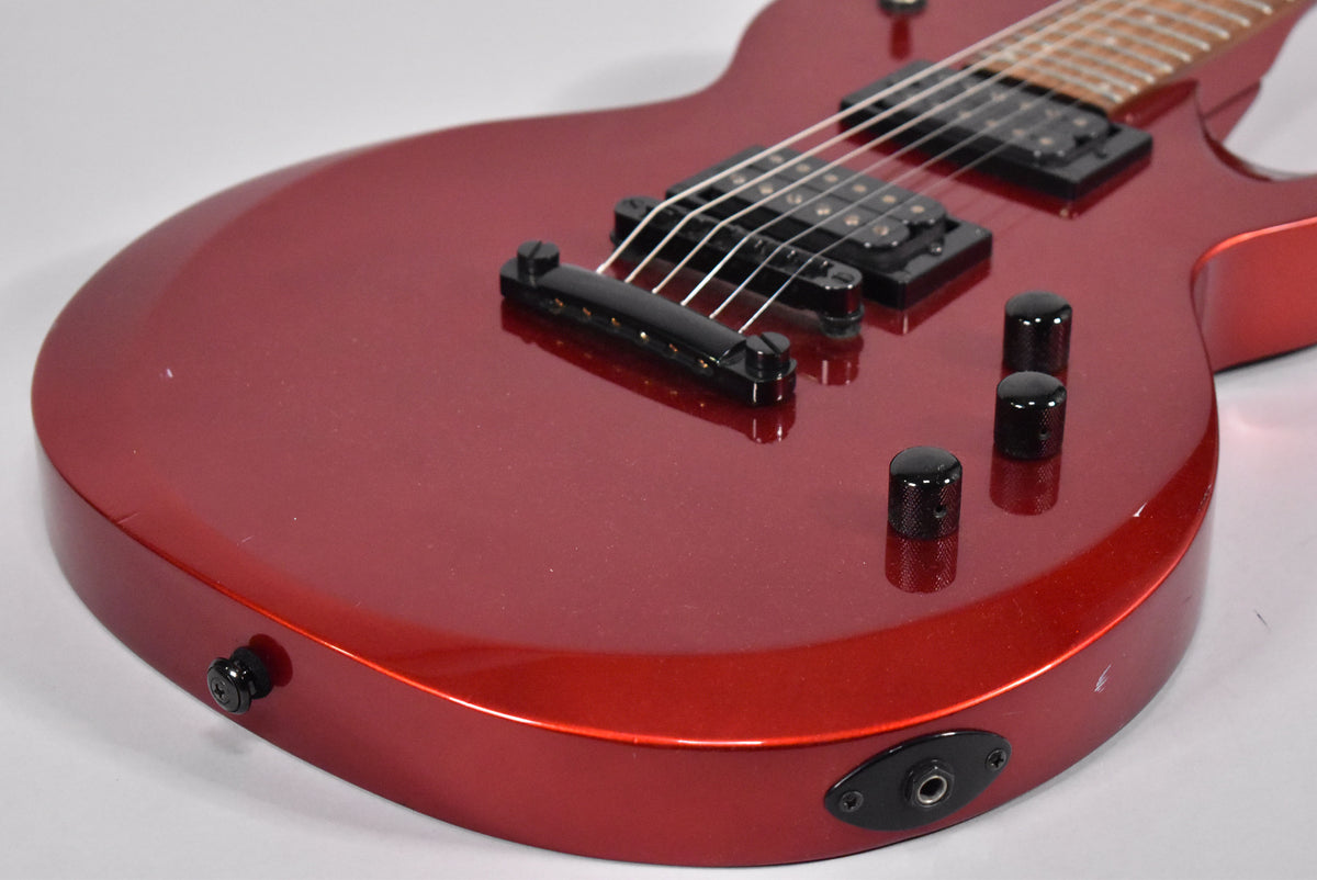 Upper body of a metallic red electric guitar with black hardware, showing two humbuckers, three control knobs, and output jack.