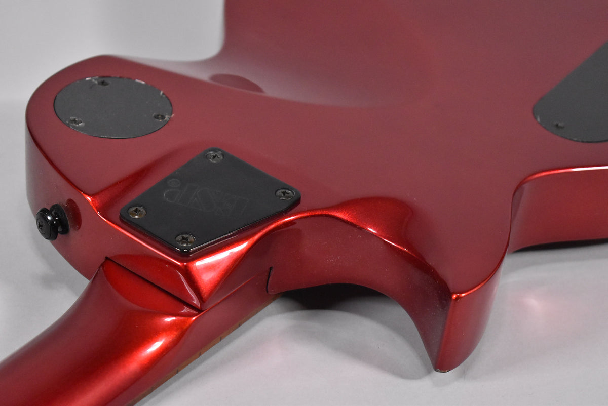 The back of a metallic red electric guitar, showing the neck joint, output jack, and control cavity covers.