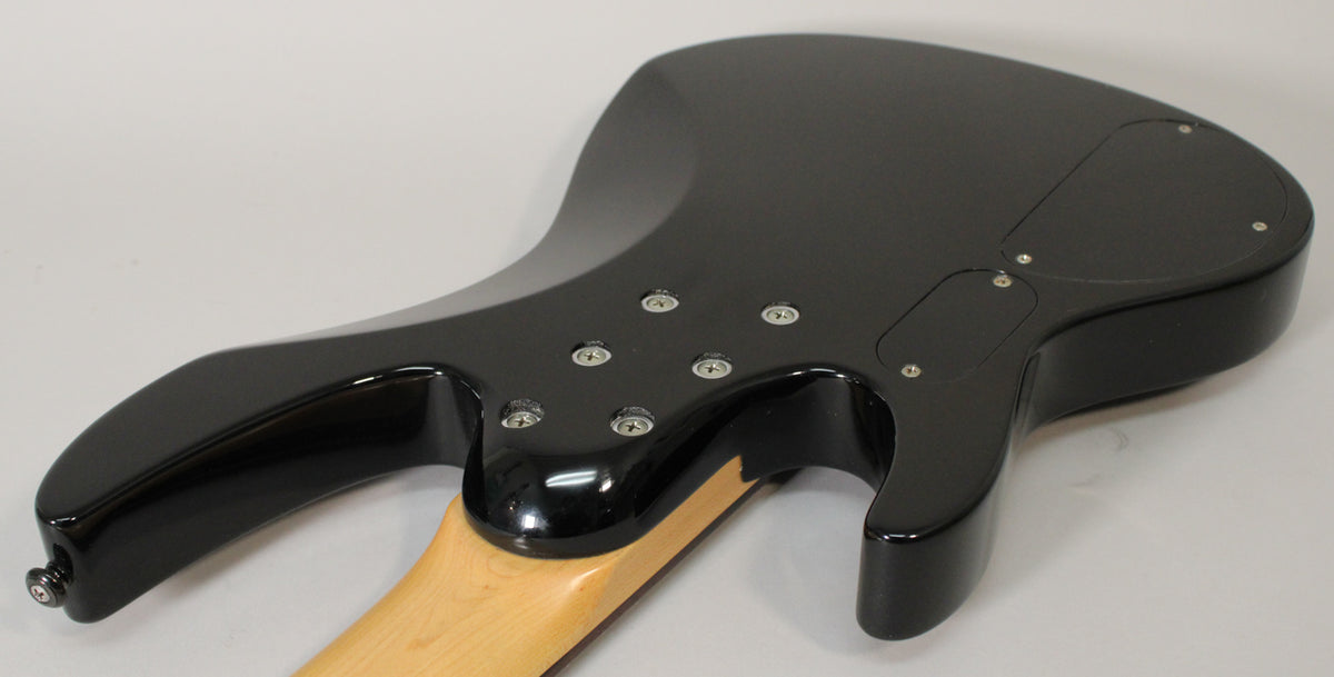 Rear view of a glossy black bass guitar body, showing the neck joint with six screws and two control cavity covers.