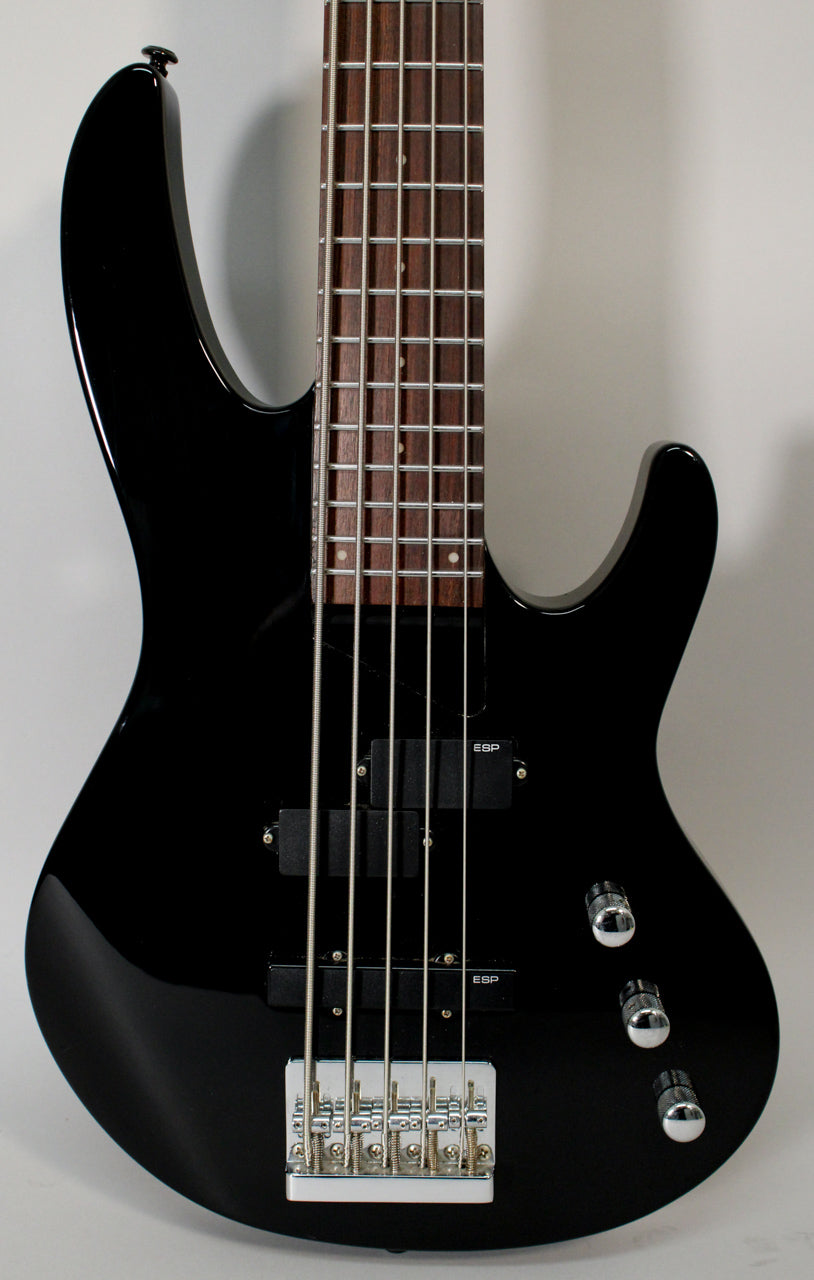 Upper body of a glossy black 5-string bass, angled slightly right, showing two pickups, chrome bridge, and three chrome knobs.