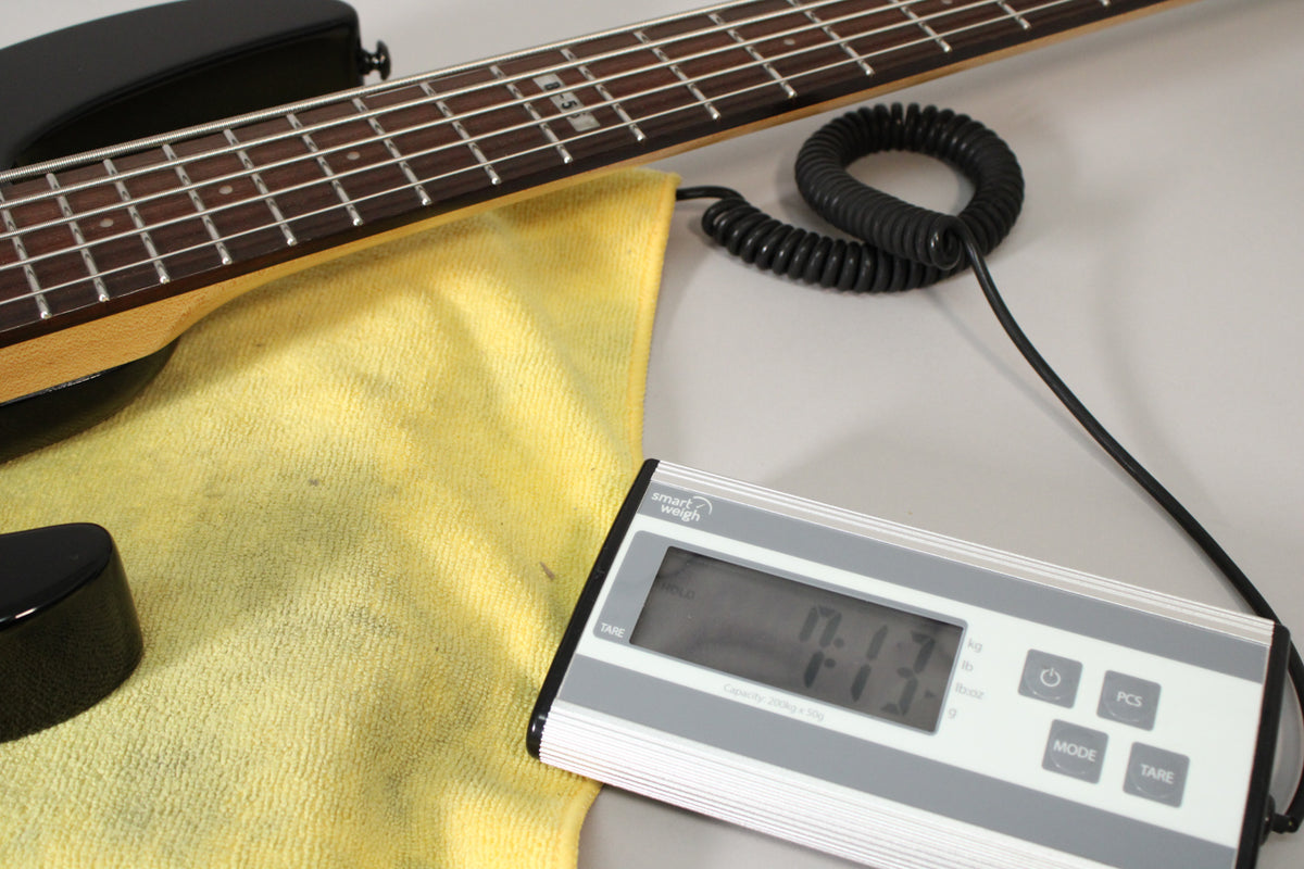 The bass neck and upper body rest on a yellow cloth, with a digital scale displaying "7.13" in the foreground.