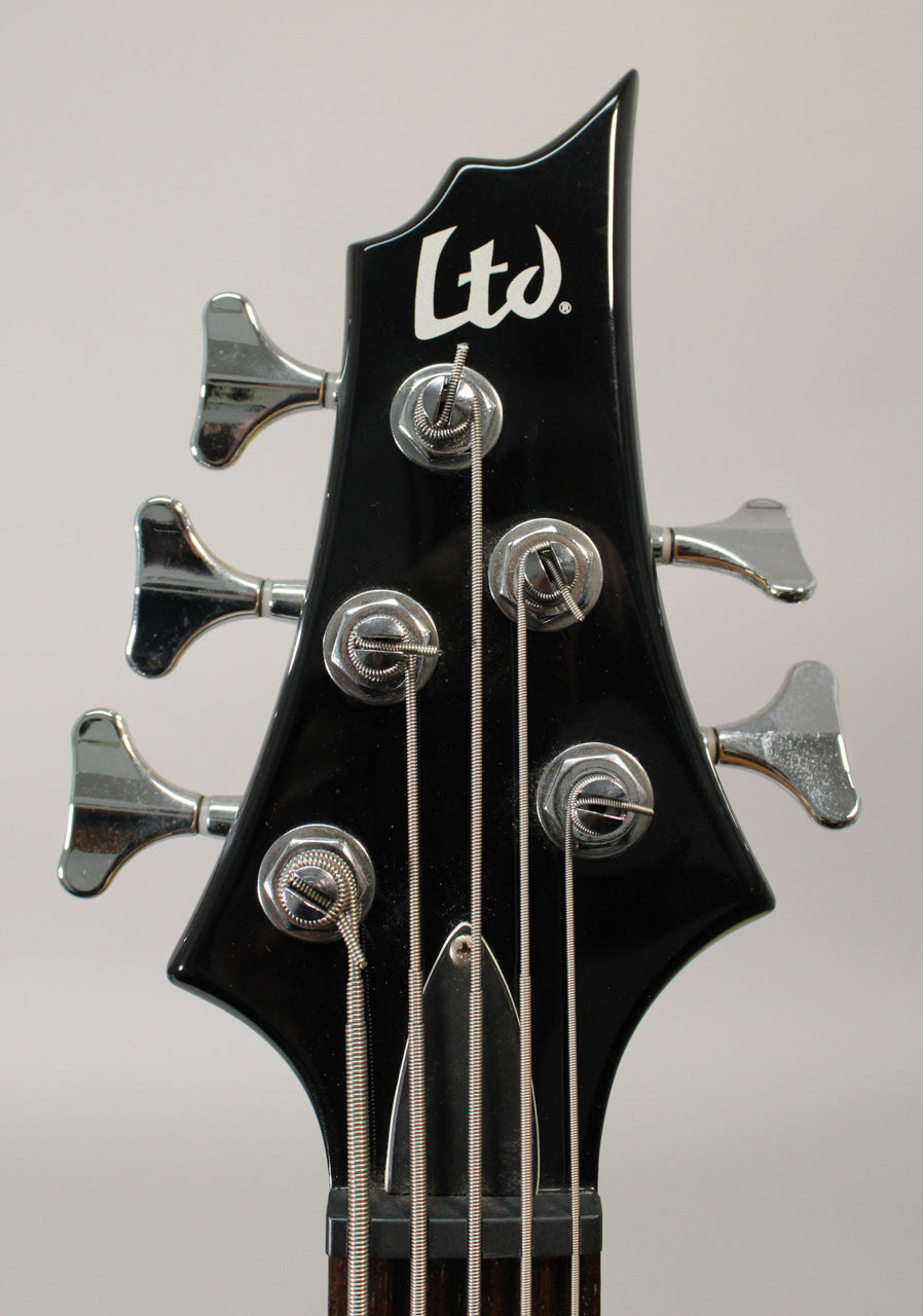 Close-up of the black gloss headstock with five chrome tuners, showing the top of the nut and string tree.
