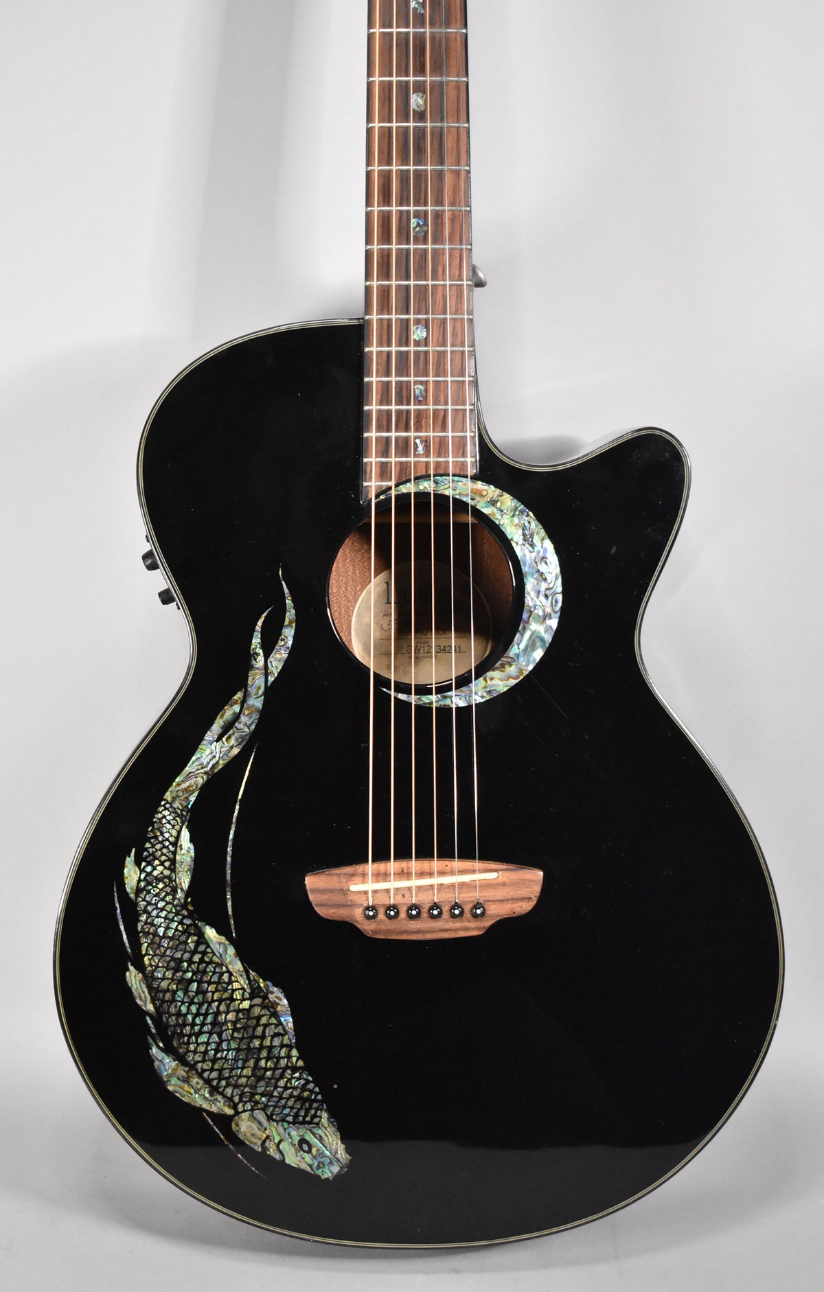 A black acoustic guitar with a cutaway, abalone koi inlay on the lower bout, and a matching abalone rosette.