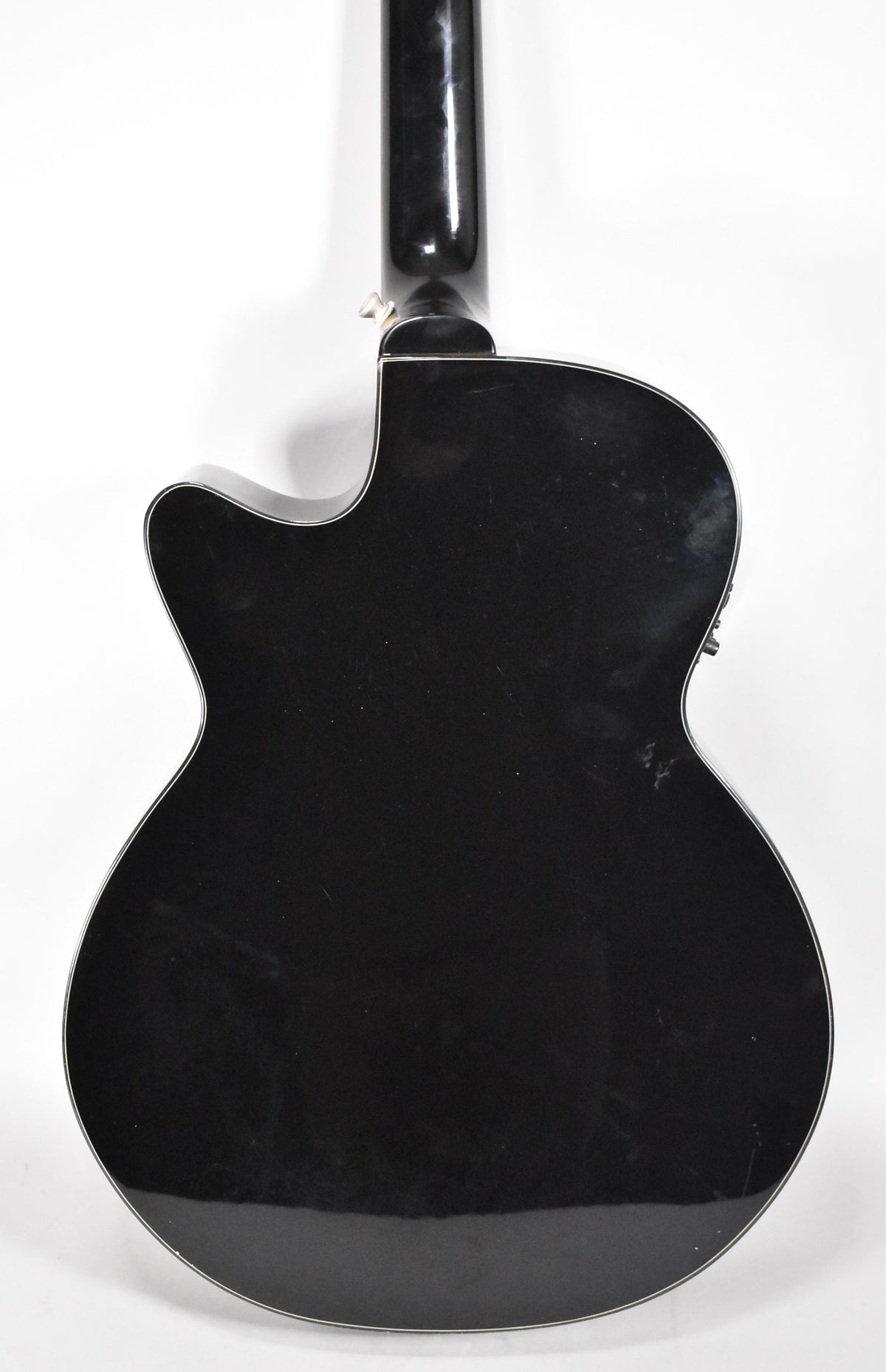 The black acoustic-electric guitar is viewed from the back, showing a glossy finish with light surface scratches and a cutaway.