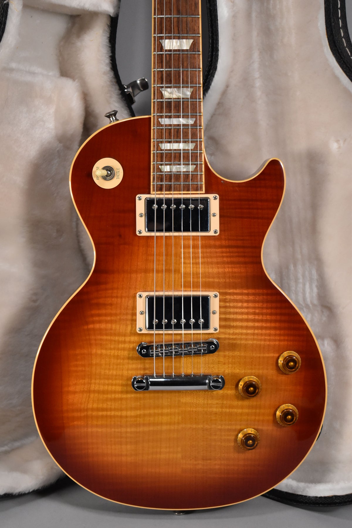 Full body of a cherry sunburst electric guitar with a flamed maple top, cream binding, two humbuckers, and four amber control knobs.