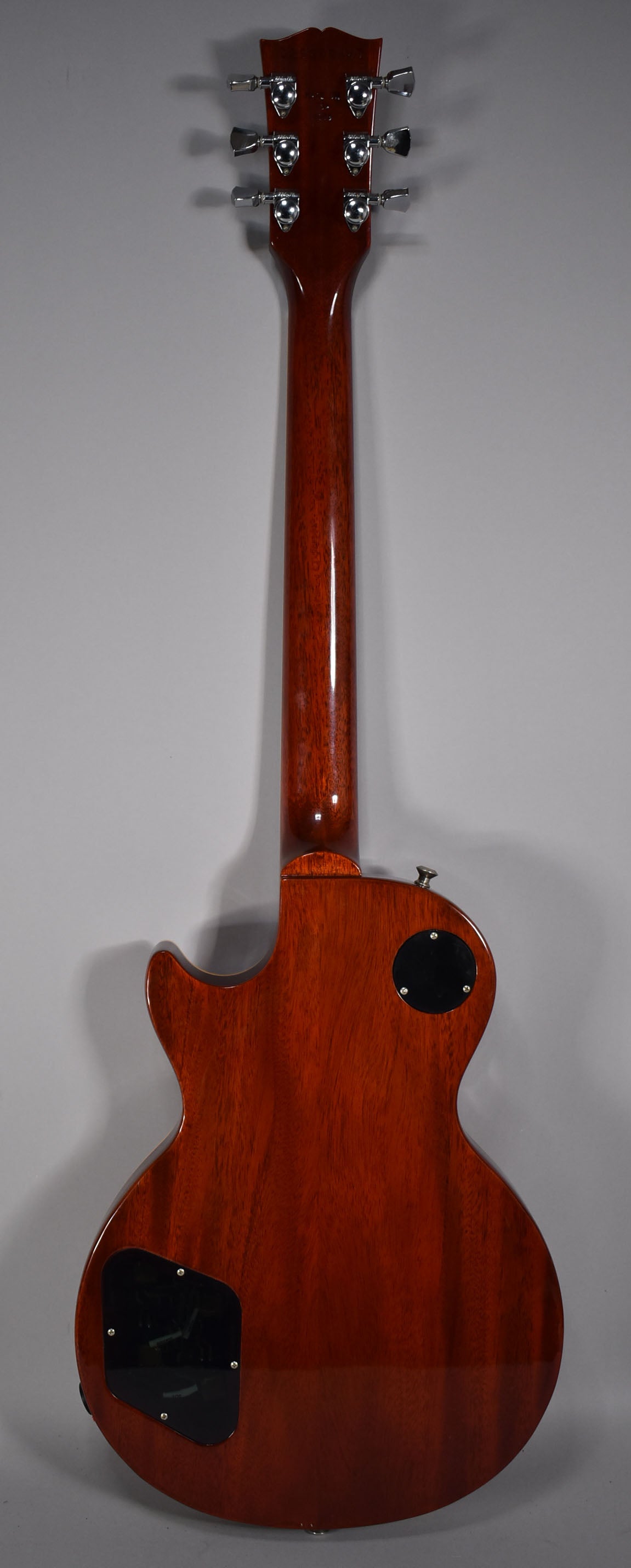 The back of a cherry sunburst electric guitar, showing the neck, headstock with six chrome tuners, and two black control plates.
