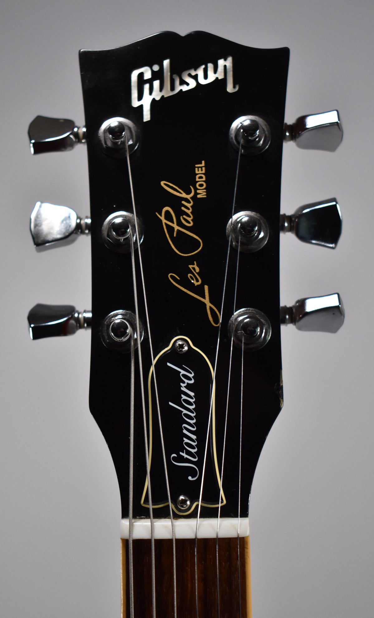 Close-up of the black headstock with chrome tuners, showing light wear around the edges and a white nut.