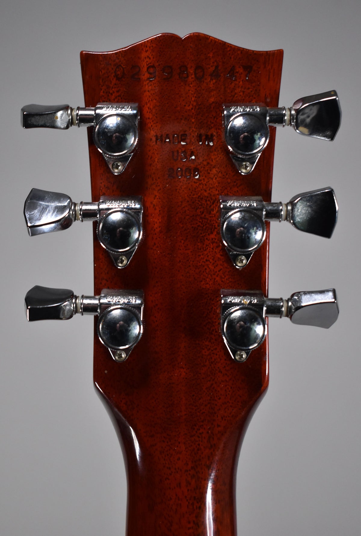 Rear view of the cherry sunburst headstock and upper neck, showing six chrome tuners and light finish checking.