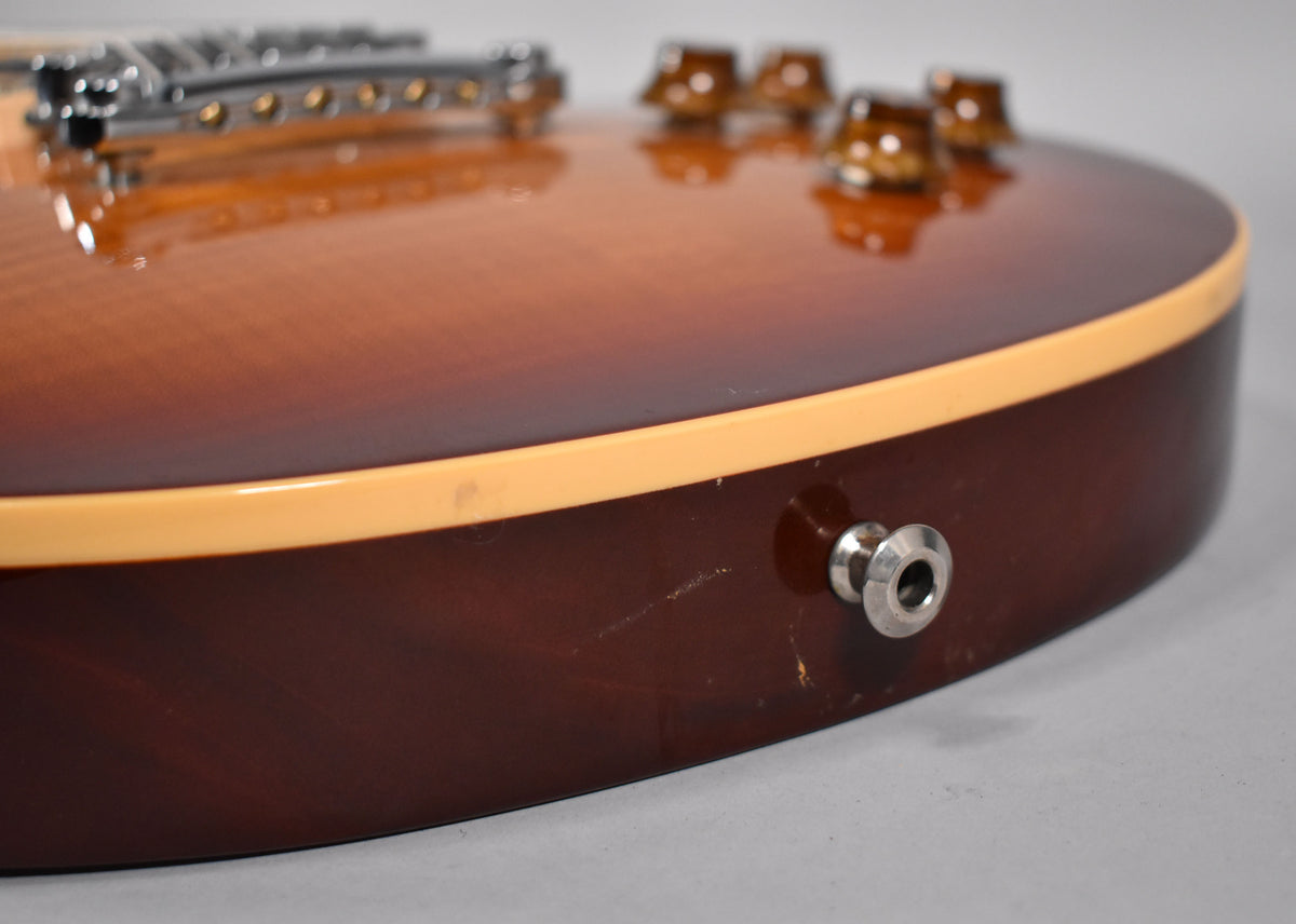 Close-up of the guitar's lower bout, showing the cherry sunburst top, cream binding, output jack, and light scratches on the dark back.