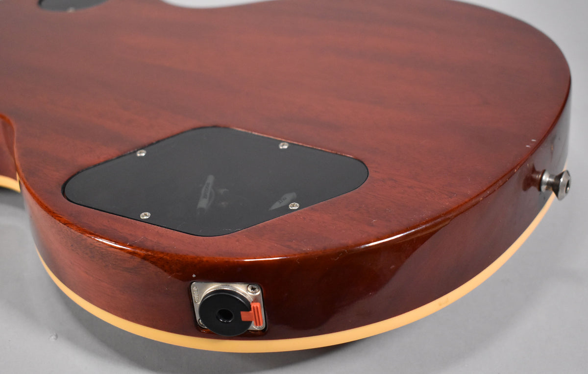 Close-up of the guitar's cherry sunburst back, showing the black control cavity cover, output jack, and strap button.