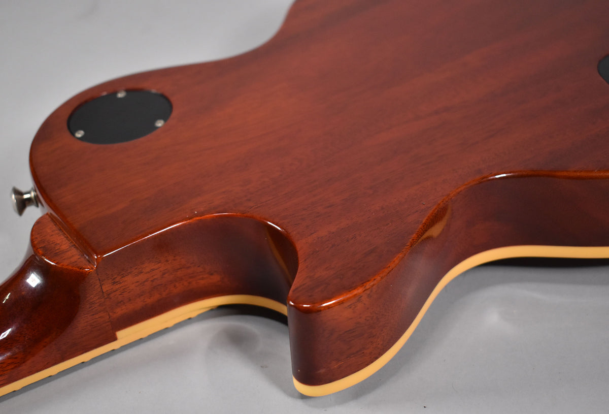 The back of the guitar shows a rich cherry sunburst finish, cream binding, and a black control cavity cover with minor wear.