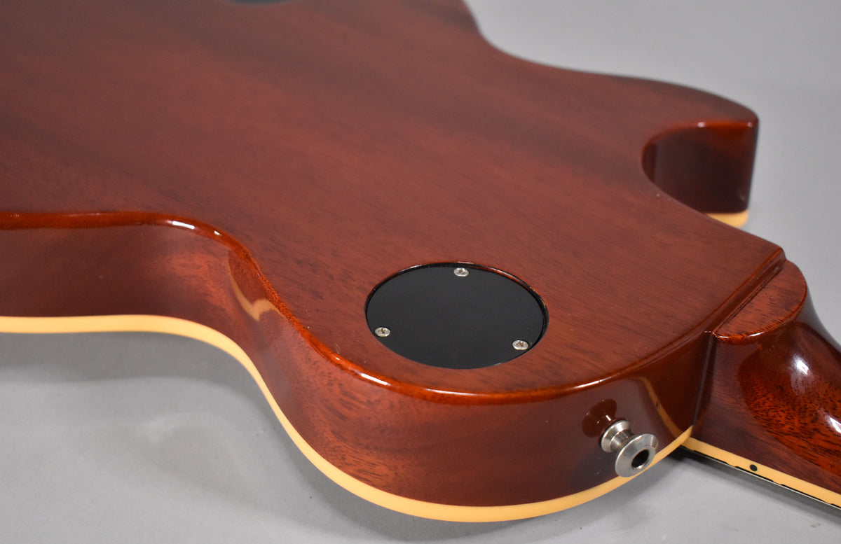 The guitar's dark cherry back and sides are visible, with a black control cavity cover and a chrome output jack.