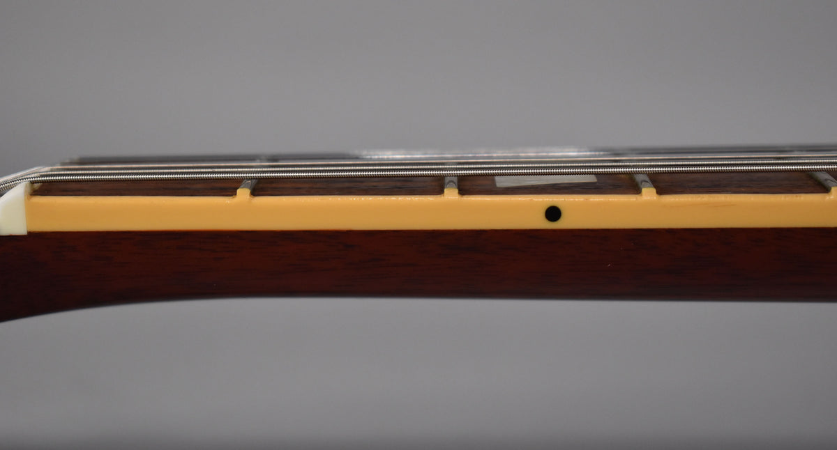 Close-up of the guitar neck's bass side, showing the dark rosewood fretboard, cream binding, and a black side dot marker.